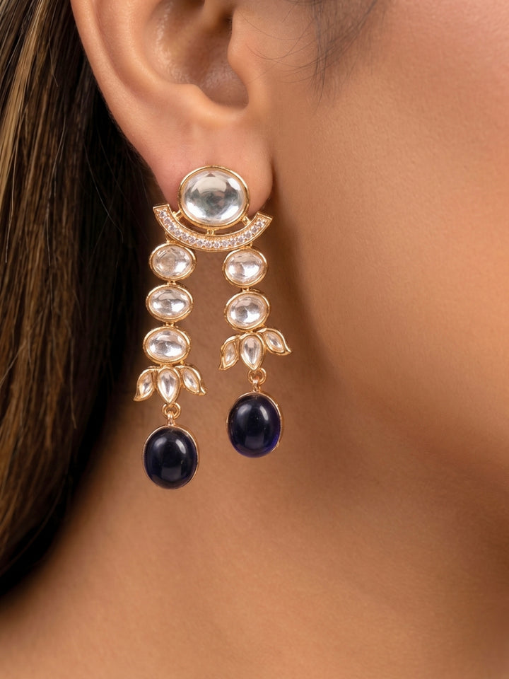 Close-up of a woman wearing an ornate traditional (Gold Polish) Navy Blue Layered jewellery set and earrings with Polki and Navy Blue Colored Stones. Wedding guest wearing a statement Polki artificial necklace for a reception party. Woman styling a premium Polki imitation necklace for wedding celebrations.