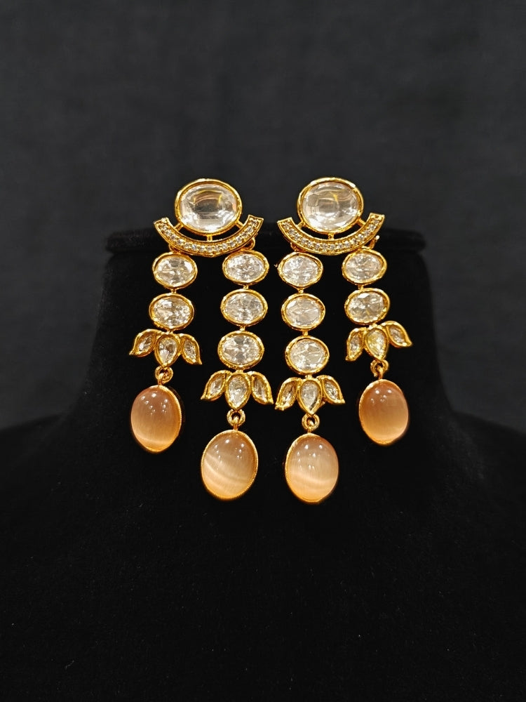 Close-up of an ornate traditional (Gold Polish) Peach Layered jewellery set and earrings with Polki and Peach Colored Stones. Wedding guest wearing a statement Polki artificial necklace for a reception party. Woman styling a premium Polki imitation necklace for wedding celebrations.