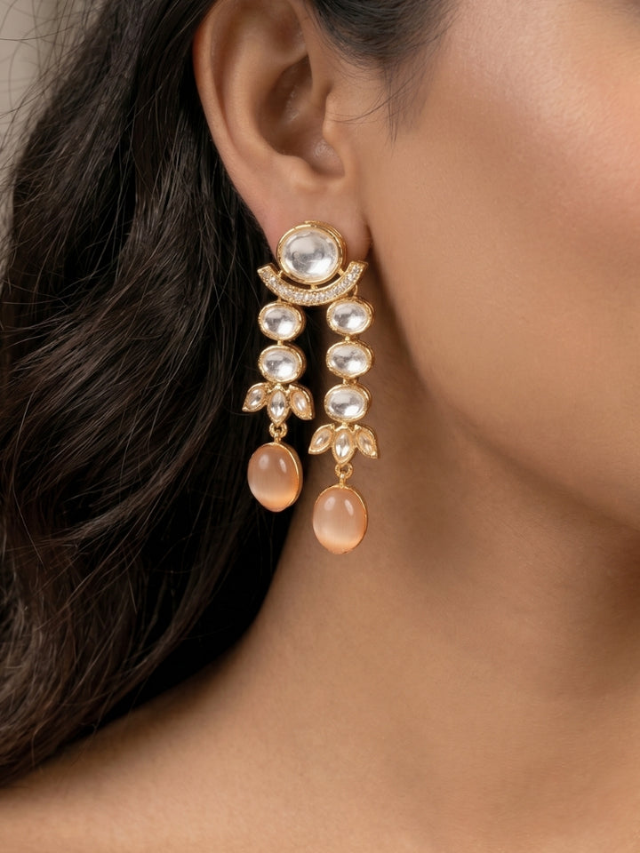 Close-up of a woman wearing an ornate traditional (Gold Polish) Peach Layered jewellery set and earrings with Polki and Peach Colored Stones. Wedding guest wearing a statement Polki artificial necklace for a reception party. Woman styling a premium Polki imitation necklace for wedding celebrations.