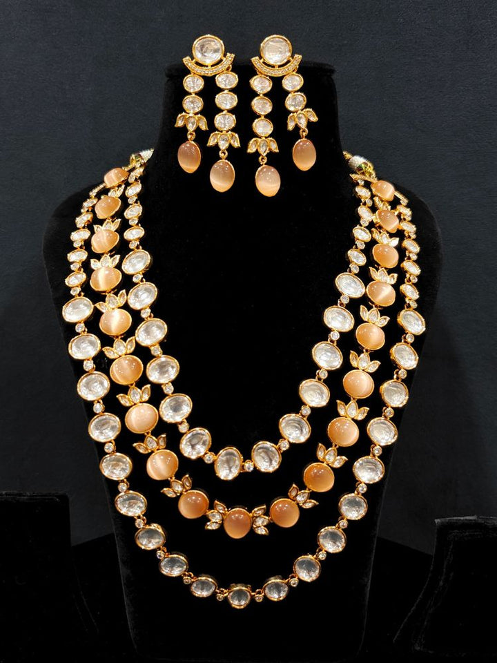 Close-up of an ornate traditional (Gold Polish) Peach Layered jewellery set and earrings with Polki and Peach Colored Stones. Wedding guest wearing a statement Polki artificial necklace for a reception party. Woman styling a premium Polki imitation necklace for wedding celebrations.