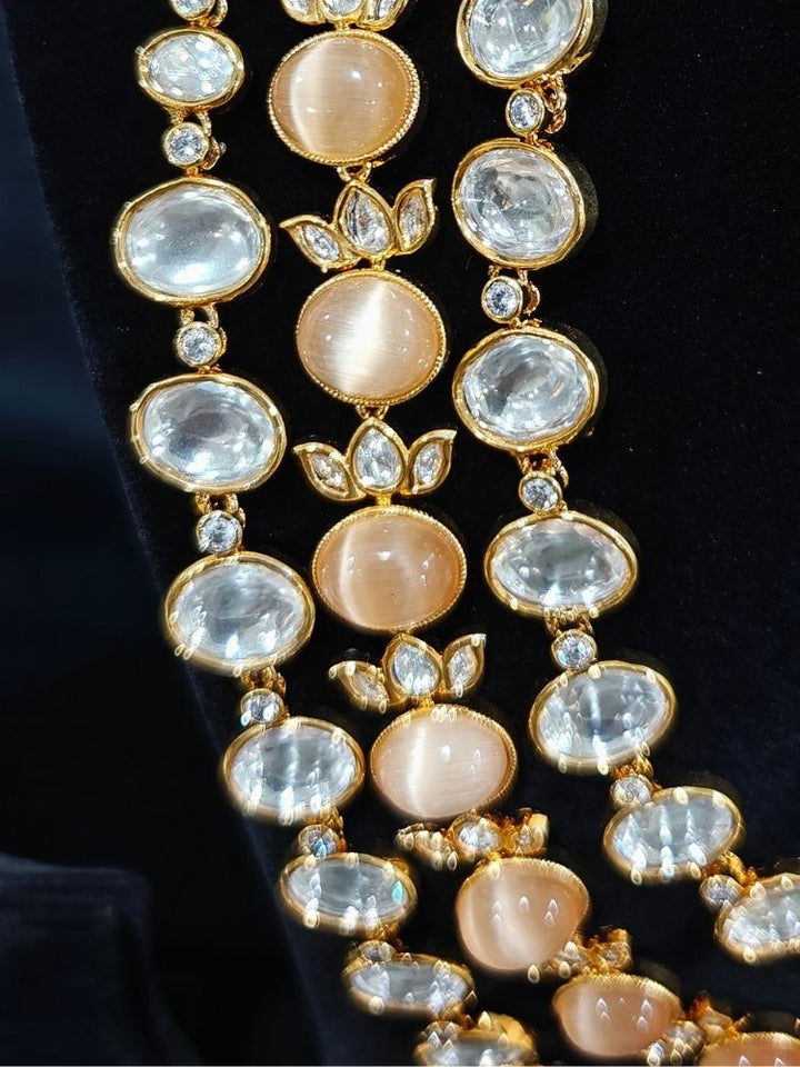 Close-up of an ornate traditional (Gold Polish) Peach Layered jewellery set and earrings with Polki and Peach Colored Stones. Wedding guest wearing a statement Polki artificial necklace for a reception party. Woman styling a premium Polki imitation necklace for wedding celebrations.
