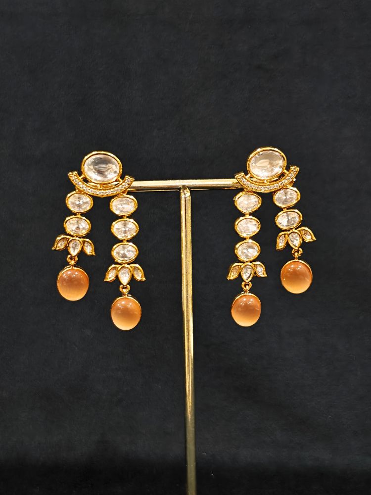 Close-up of an ornate traditional (Gold Polish) Peach Layered jewellery set and earrings with Polki and Peach Colored Stones. Wedding guest wearing a statement Polki artificial necklace for a reception party. Woman styling a premium Polki imitation necklace for wedding celebrations.