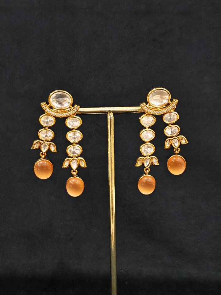 Close-up of an ornate traditional (Gold Polish) Peach Layered jewellery set and earrings with Polki and Peach Colored Stones. Wedding guest wearing a statement Polki artificial necklace for a reception party. Woman styling a premium Polki imitation necklace for wedding celebrations.