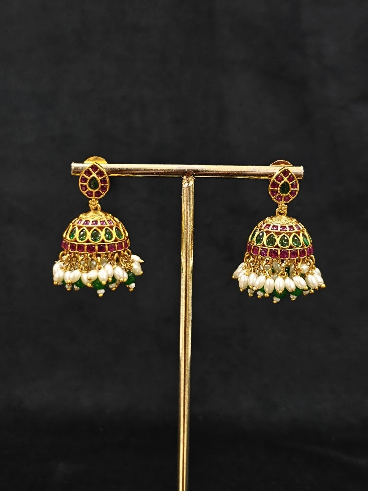 Close-up of an ornate traditional (Gold Polish) Green Collar jewellery set and earrings with Green & Pink Colored Stones, Green Beads and Pearls. Mehendi ceremony look completed with a handcrafted Colored Stones jewelry set. Saree look completed with an elegant Colored Stones artificial jewelry piece.