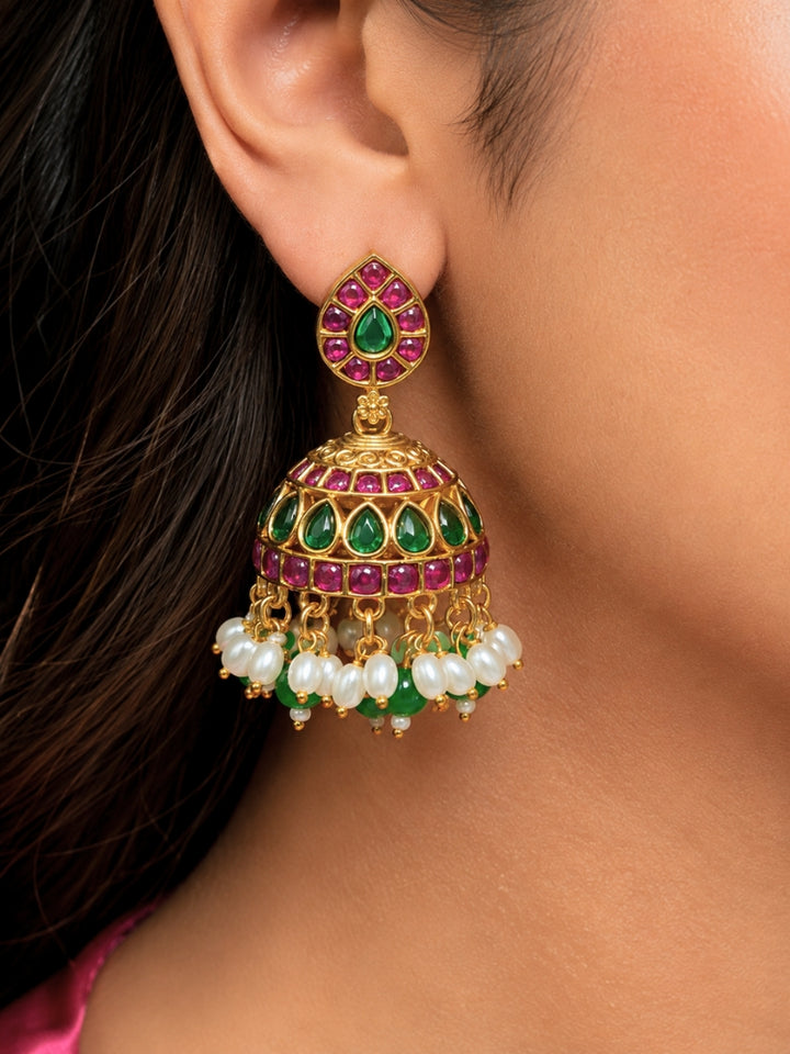 Close-up of a women wearing an ornate traditional (Gold Polish) Green Collar jewellery set and earrings with Green & Pink Colored Stones, Green Beads and Pearls. Mehendi ceremony look completed with a handcrafted Colored Stones jewelry set. Saree look completed with an elegant Colored Stones artificial jewelry piece.