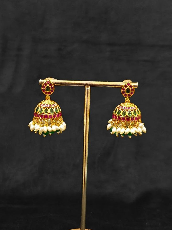 Close-up of an ornate traditional (Gold Polish) Green Collar jewellery set and earrings with Green & Pink Colored Stones, Green Beads and Pearls. Mehendi ceremony look completed with a handcrafted Colored Stones jewelry set. Saree look completed with an elegant Colored Stones artificial jewelry piece.
