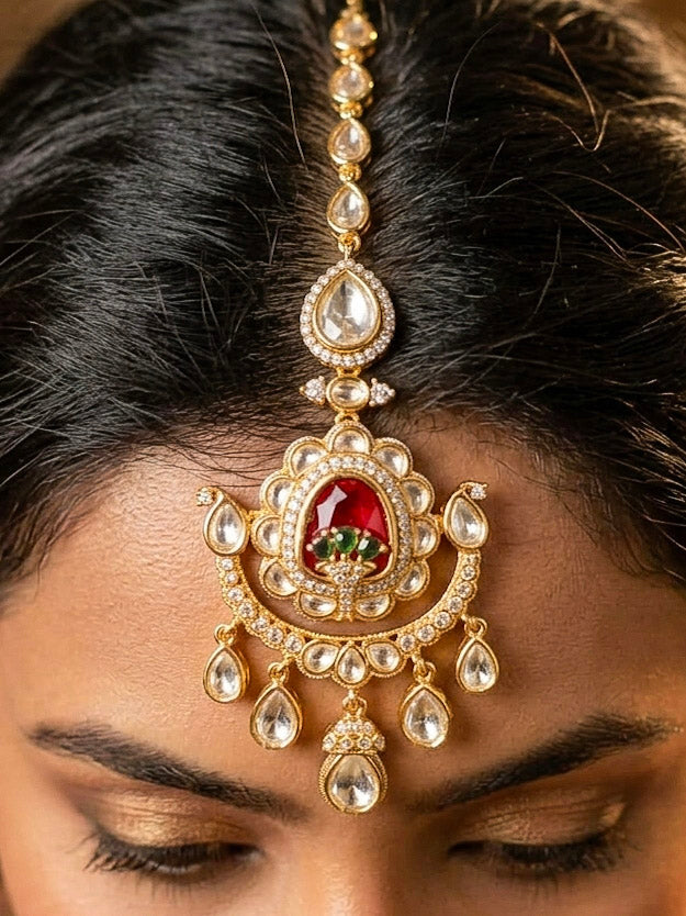 Close-up of a woman wearing an ornate traditional (Bright Gold) Red and Green Choker jewellery set and earrings and maangtikka with Uncut Kundan, American Diamond, Green Colored Stones, Pearls and Doublet Stone. Bride showcasing a premium imitation Moissanite jewelry set for her reception look. Wedding celebration styling with a luxury artificial Moissanite jewelry Set design.