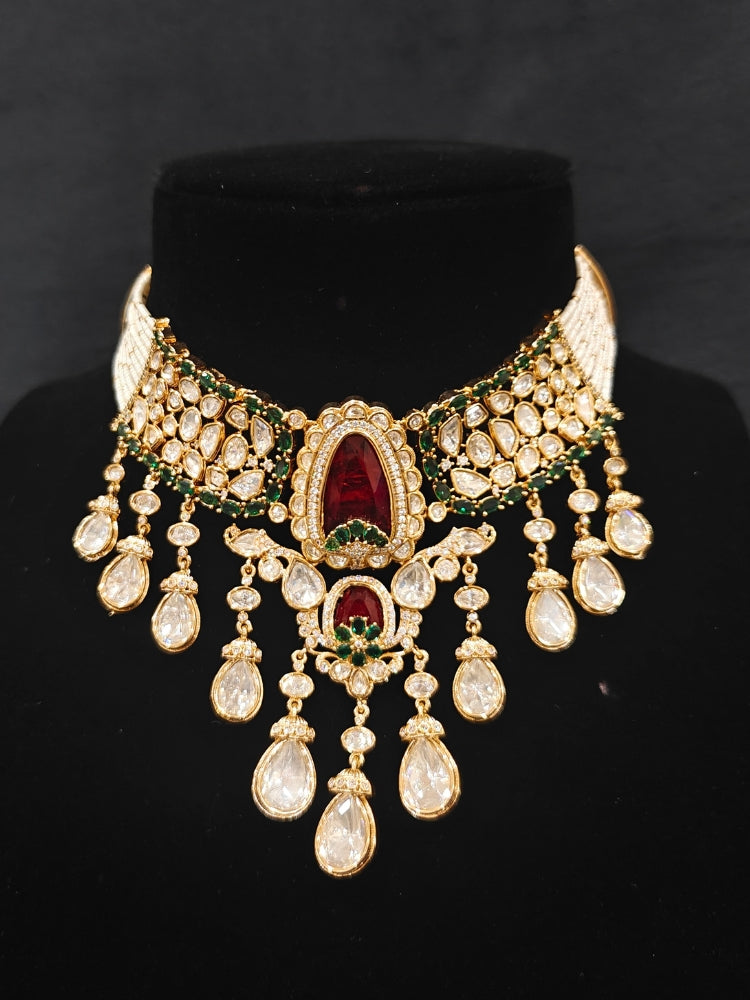 Close-up of an ornate traditional (Bright Gold) Red and Green Choker jewellery set and earrings and maangtikka with Uncut Kundan, American Diamond, Green Colored Stones, Pearls and Doublet Stone. Bride showcasing a premium imitation Moissanite jewelry set for her reception look. Wedding celebration styling with a luxury artificial Moissanite jewelry Set design.