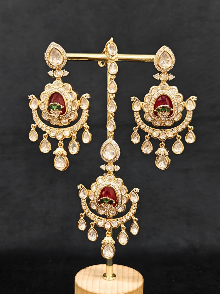 Close-up of an ornate traditional (Bright Gold) Red and Green Choker jewellery set and earrings and maangtikka with Uncut Kundan, American Diamond, Green Colored Stones, Pearls and Doublet Stone. Bride showcasing a premium imitation Moissanite jewelry set for her reception look. Wedding celebration styling with a luxury artificial Moissanite jewelry Set design.