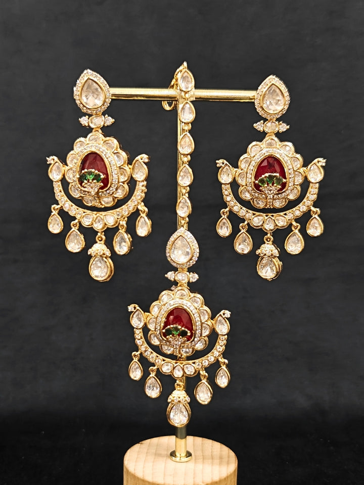 Close-up of an ornate traditional (Bright Gold) Red and Green Choker jewellery set and earrings and maangtikka with Uncut Kundan, American Diamond, Green Colored Stones, Pearls and Doublet Stone. Bride showcasing a premium imitation Moissanite jewelry set for her reception look. Wedding celebration styling with a luxury artificial Moissanite jewelry Set design.