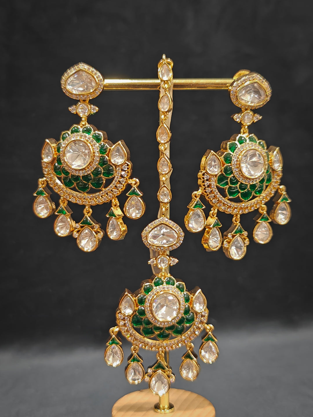 Close-up of an ornate traditional (Bright Gold) Green Collar jewellery set and earrings and maangtikka with Green Colored Stones, American Diamond, Pearls and Moissanite. Reception night styling featuring sparkling imitation Moissanite jewelry Set. Bride wearing a high-quality artificial Moissanite jewelry set for wedding rituals.