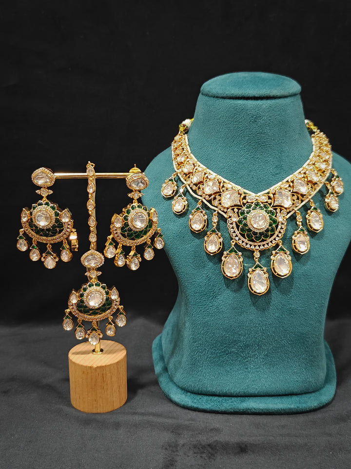 Close-up of an ornate traditional (Bright Gold) Green Collar jewellery set and earrings and maangtikka with Green Colored Stones, American Diamond, Pearls and Moissanite. Reception night styling featuring sparkling imitation Moissanite jewelry Set. Bride wearing a high-quality artificial Moissanite jewelry set for wedding rituals.