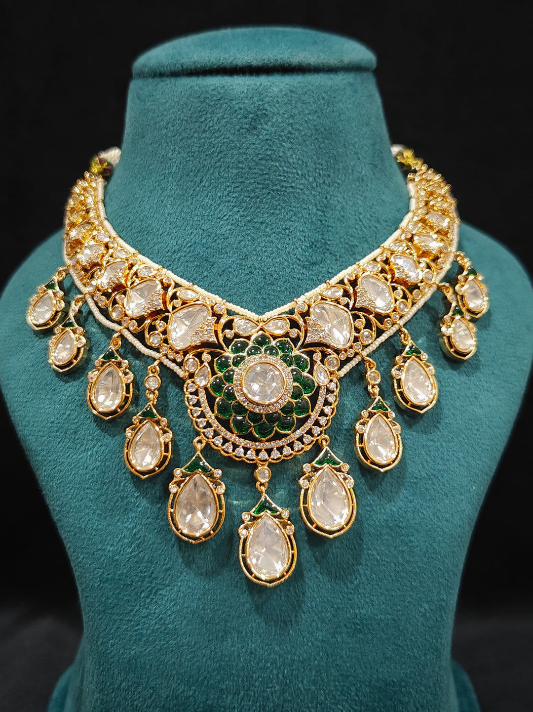 Close-up of an ornate traditional (Bright Gold) Green Collar jewellery set and earrings and maangtikka with Green Colored Stones, American Diamond, Pearls and Moissanite. Reception night styling featuring sparkling imitation Moissanite jewelry Set. Bride wearing a high-quality artificial Moissanite jewelry set for wedding rituals.