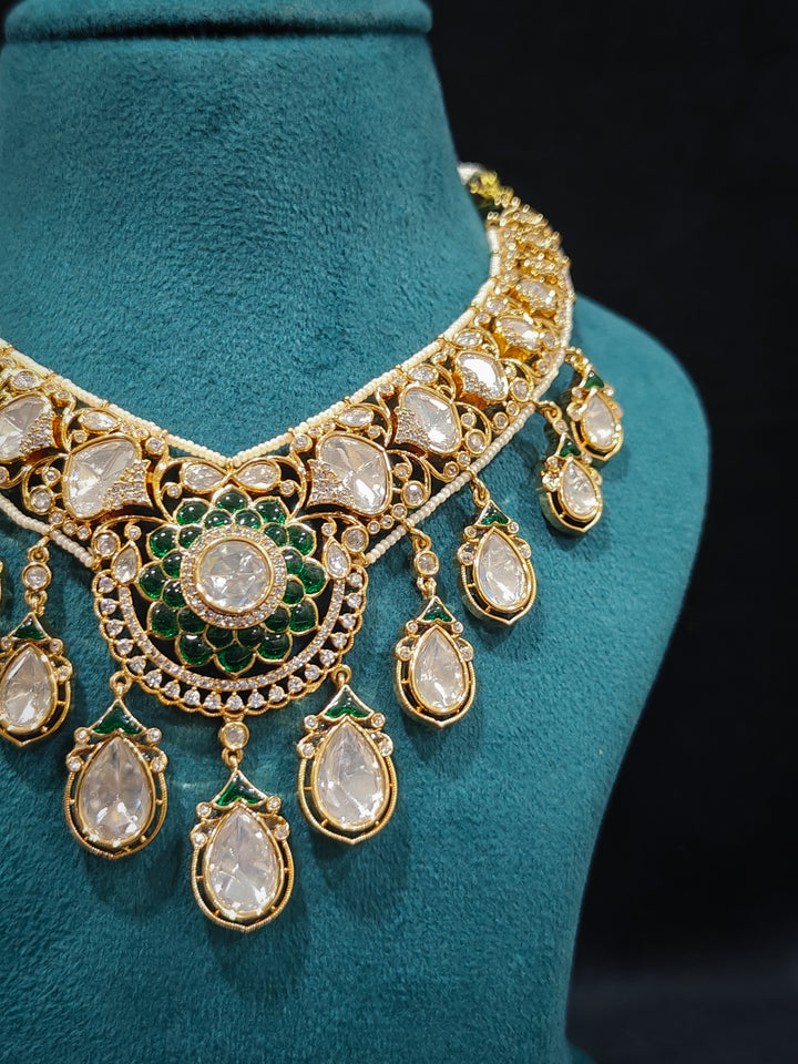 Close-up of an ornate traditional (Bright Gold) Green Collar jewellery set and earrings and maangtikka with Green Colored Stones, American Diamond, Pearls and Moissanite. Reception night styling featuring sparkling imitation Moissanite jewelry Set. Bride wearing a high-quality artificial Moissanite jewelry set for wedding rituals.