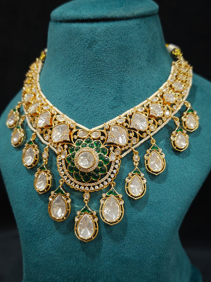 Close-up of an ornate traditional (Bright Gold) Green Collar jewellery set and earrings and maangtikka with Green Colored Stones, American Diamond, Pearls and Moissanite. Reception night styling featuring sparkling imitation Moissanite jewelry Set. Bride wearing a high-quality artificial Moissanite jewelry set for wedding rituals.