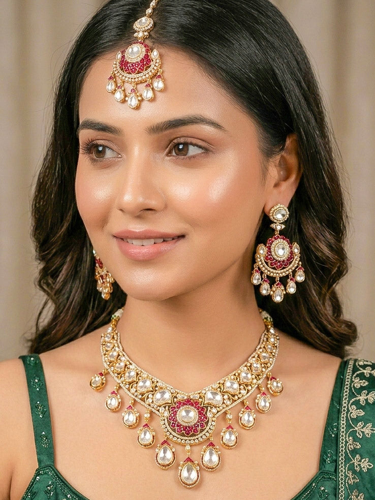 Close-up of a woman wearing an ornate traditional (Bright Gold) Red Collar jewellery set and earrings and maangtikka with Red Colored Stones, American Diamond, Pearls and Moissanite. Reception night styling featuring sparkling imitation Moissanite jewelry Set. Bride wearing a high-quality artificial Moissanite jewelry set for wedding rituals.