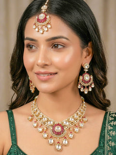 Close-up of a woman wearing an ornate traditional (Bright Gold) Red Collar jewellery set and earrings and maangtikka with Red Colored Stones, American Diamond, Pearls and Moissanite. Reception night styling featuring sparkling imitation Moissanite jewelry Set. Bride wearing a high-quality artificial Moissanite jewelry set for wedding rituals.