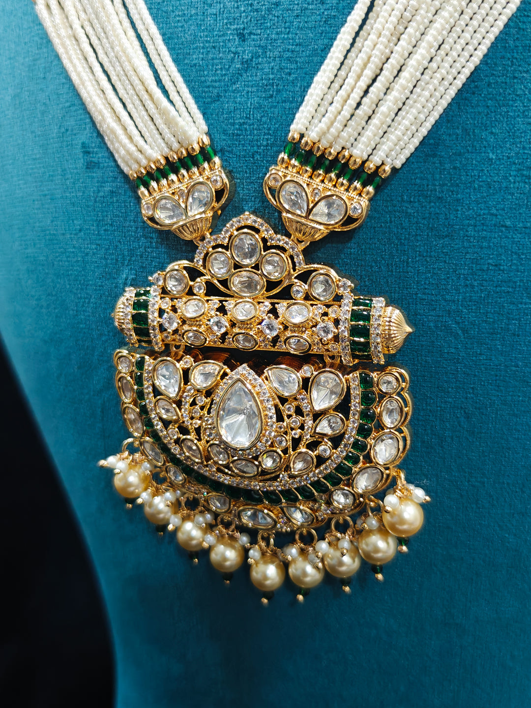 Close-up of an ornate traditional (Bright Gold) Green long jewellery set and earrings with Moissanite Polki, American Diamond, Green Colored Stones, Pearls, Beads and Hydro Crystals. Woman wearing Long artificial Moissanite jewelry for a grand celebration. Bride wearing a high-quality artificial Moissanite jewelry set for wedding rituals.