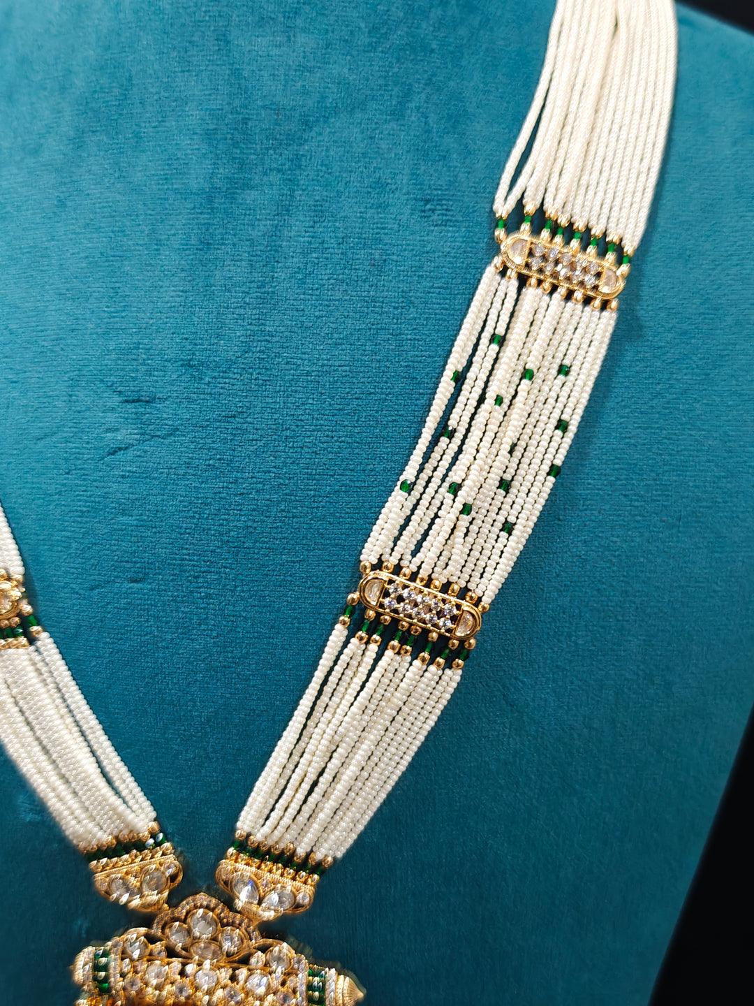 Close-up of an ornate traditional (Bright Gold) Green long jewellery set and earrings with Moissanite Polki, American Diamond, Green Colored Stones, Pearls, Beads and Hydro Crystals. Woman wearing Long artificial Moissanite jewelry for a grand celebration. Bride wearing a high-quality artificial Moissanite jewelry set for wedding rituals.
