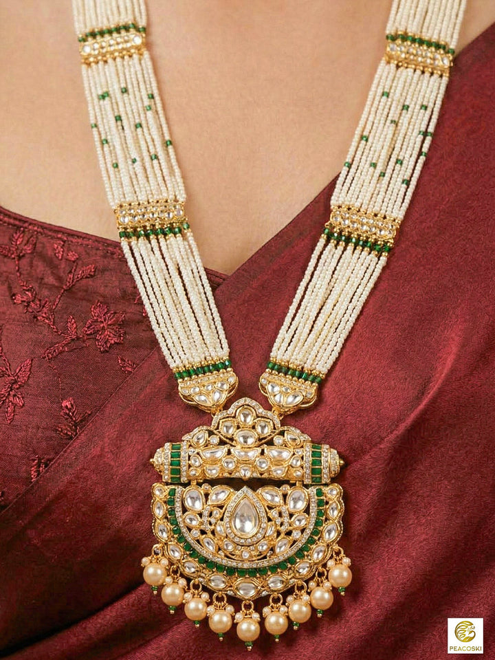 Close-up of a woman wearing an ornate traditional (Bright Gold) Green long jewellery set and earrings with Moissanite Polki, American Diamond, Green Colored Stones, Pearls, Beads and Hydro Crystals. Woman wearing Long artificial Moissanite jewelry for a grand celebration. Bride wearing a high-quality artificial Moissanite jewelry set for wedding rituals.