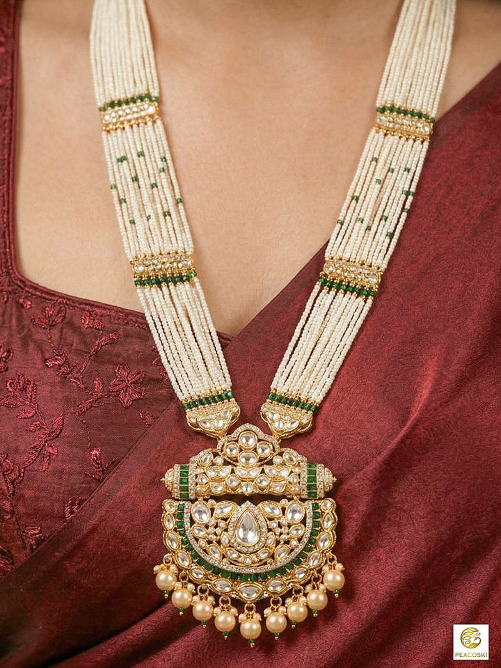 Close-up of a woman wearing an ornate traditional (Bright Gold) Green long jewellery set and earrings with Moissanite Polki, American Diamond, Green Colored Stones, Pearls, Beads and Hydro Crystals. Woman wearing Long artificial Moissanite jewelry for a grand celebration. Bride wearing a high-quality artificial Moissanite jewelry set for wedding rituals.