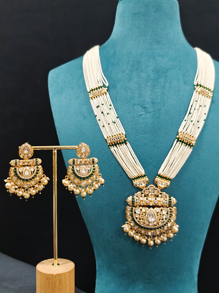 Close-up of an ornate traditional (Bright Gold) Green long jewellery set and earrings with Moissanite Polki, American Diamond, Green Colored Stones, Pearls, Beads and Hydro Crystals. Woman wearing Long artificial Moissanite jewelry for a grand celebration. Bride wearing a high-quality artificial Moissanite jewelry set for wedding rituals.