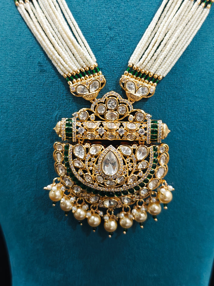 Close-up of an ornate traditional (Bright Gold) Green long jewellery set and earrings with Moissanite Polki, American Diamond, Green Colored Stones, Pearls, Beads and Hydro Crystals. Woman wearing Long artificial Moissanite jewelry for a grand celebration. Bride wearing a high-quality artificial Moissanite jewelry set for wedding rituals.