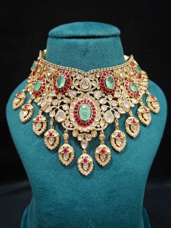 Close-up of a woman wearing an ornate traditional (Bright Gold) Mint Green and Ruby Pink Choker jewellery set and earrings and maangtikka with Doublet Stone, Moissanite, Kundan, American Diamond and Ruby Pink & Mint Green colored Stone. Bridal photoshoot look styled with a luxury imitation Moissanite jewelry set. Bride showcasing a traditional yet modern artificial Moissanite jewelry set design.