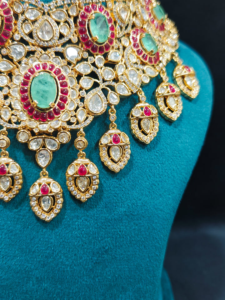 Close-up of an ornate traditional (Bright Gold) Mint Green and Ruby Pink Choker jewellery set and earrings and maangtikka with Doublet Stone, Moissanite, Kundan, American Diamond and Ruby Pink & Mint Green colored Stone. Bridal photoshoot look styled with a luxury imitation Moissanite jewelry set. Bride showcasing a traditional yet modern artificial Moissanite jewelry set design.