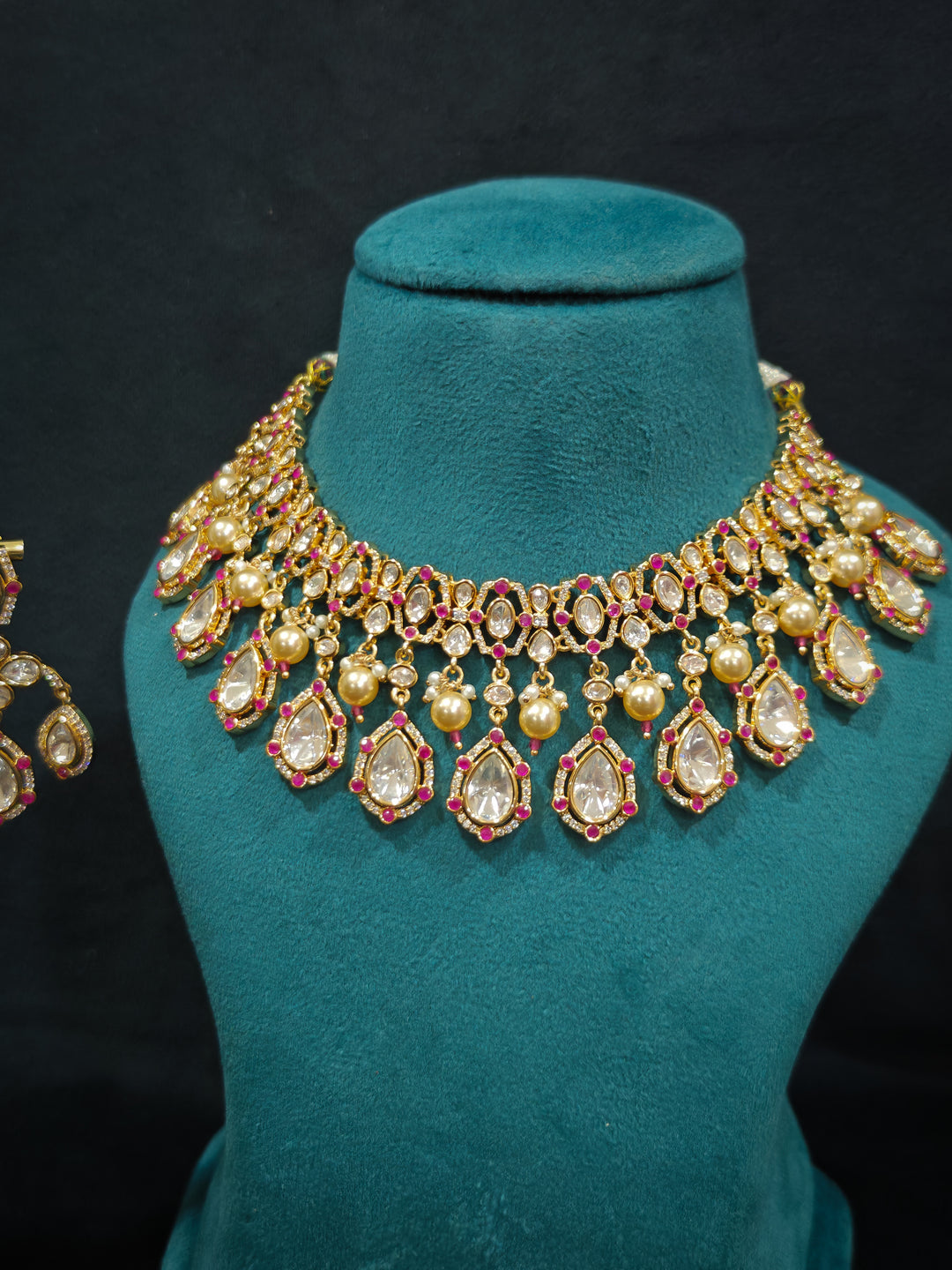 Close-up of an ornate traditional (Bright Gold) Pink Collar jewellery set and earrings and maangtikka with Kundan, Pink Colored Stones, American Diamond and Pearls. Bridal photoshoot look styled with a luxury imitation Moissanite jewelry set. Woman wearing Luxury artificial Moissanite jewelry for a grand celebration.
