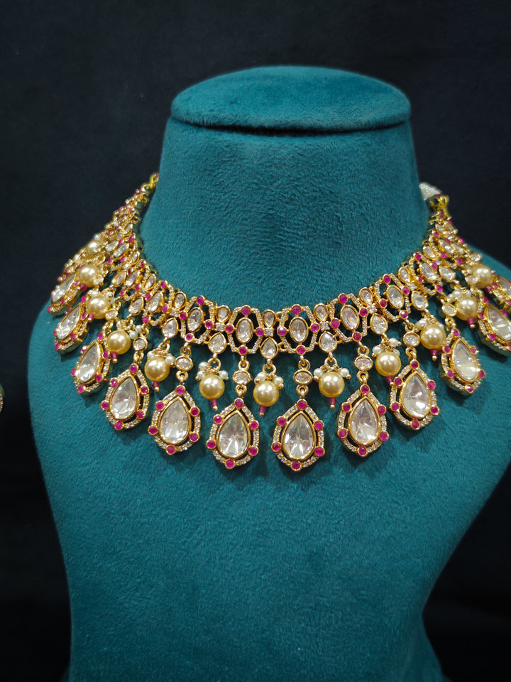 Close-up of an ornate traditional (Bright Gold) Pink Collar jewellery set and earrings and maangtikka with Kundan, Pink Colored Stones, American Diamond and Pearls. Bridal photoshoot look styled with a luxury imitation Moissanite jewelry set. Woman wearing Luxury artificial Moissanite jewelry for a grand celebration.