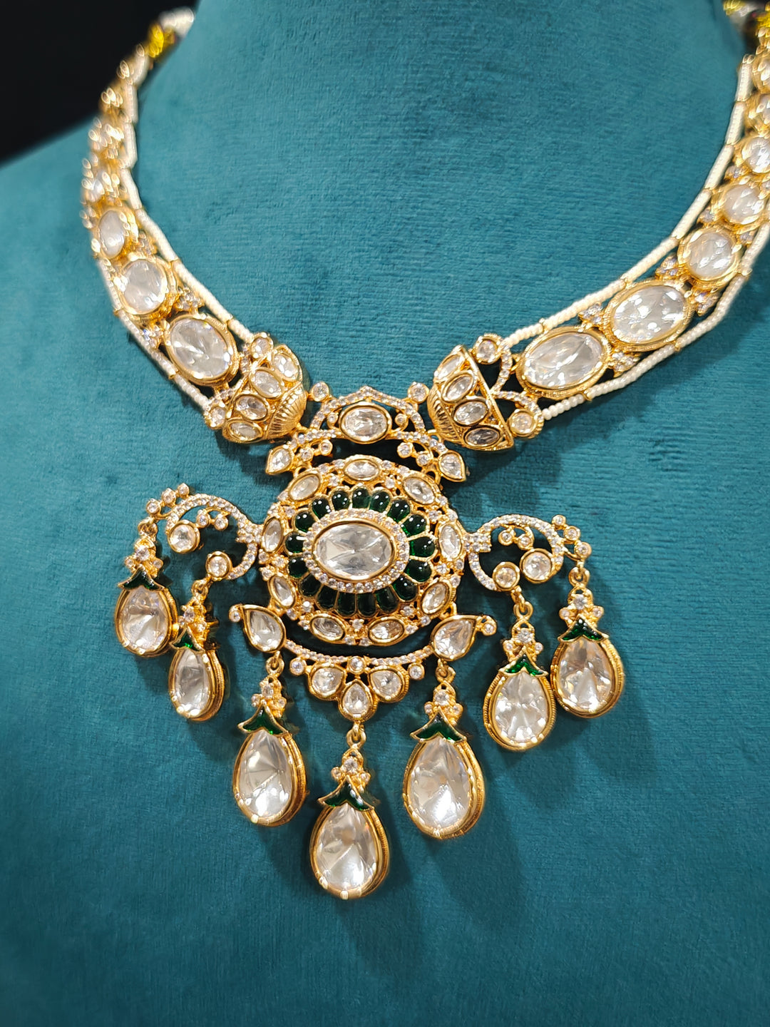 Close-up of an ornate traditional (Bright Gold) Green Collar jewellery set and earrings and maangtikka with Green Colored Stones, Kundan, American Diamond and Pearls. Woman wearing trending artificial Moissanite jewelry for wedding season in India. Bride wearing a high-quality artificial Moissanite jewelry set for wedding rituals.