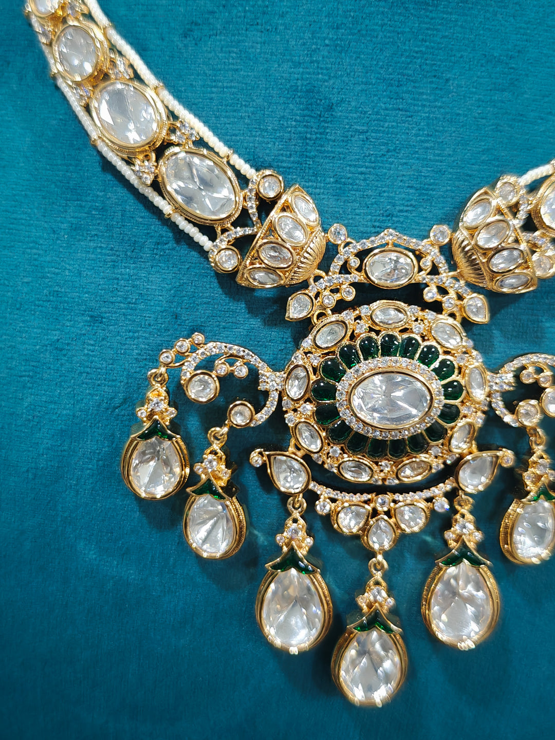 Close-up of an ornate traditional (Bright Gold) Green Collar jewellery set and earrings and maangtikka with Green Colored Stones, Kundan, American Diamond and Pearls. Woman wearing trending artificial Moissanite jewelry for wedding season in India. Bride wearing a high-quality artificial Moissanite jewelry set for wedding rituals.