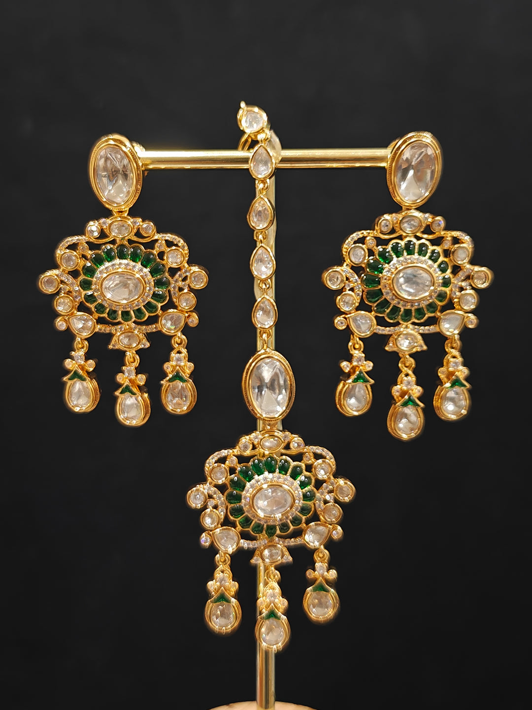 Close-up of an ornate traditional (Bright Gold) Green Collar jewellery set and earrings and maangtikka with Green Colored Stones, Kundan, American Diamond and Pearls. Woman wearing trending artificial Moissanite jewelry for wedding season in India. Bride wearing a high-quality artificial Moissanite jewelry set for wedding rituals.