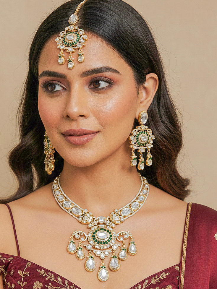 Close-up of a woman wearing an ornate traditional (Bright Gold) Green Collar jewellery set and earrings and maangtikka with Green Colored Stones, Kundan, American Diamond and Pearls. Woman wearing trending artificial Moissanite jewelry for wedding season in India. Bride wearing a high-quality artificial Moissanite jewelry set for wedding rituals.