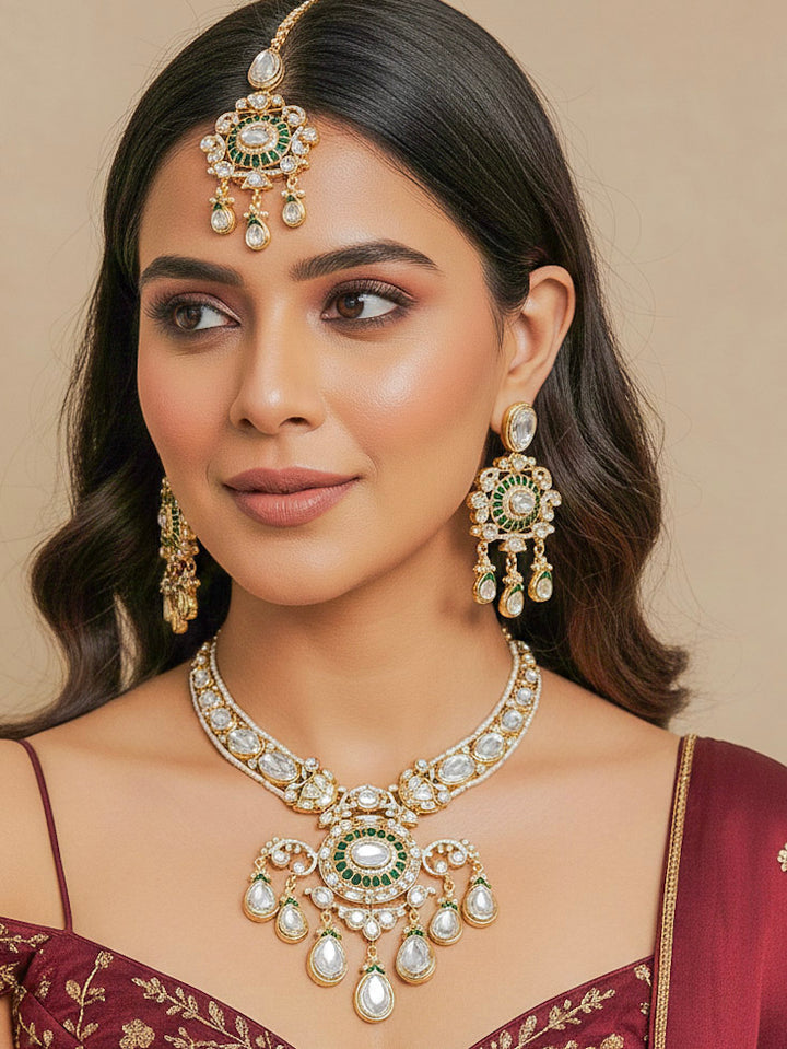Close-up of a woman wearing an ornate traditional (Bright Gold) Green Collar jewellery set and earrings and maangtikka with Green Colored Stones, Kundan, American Diamond and Pearls. Woman wearing trending artificial Moissanite jewelry for wedding season in India. Bride wearing a high-quality artificial Moissanite jewelry set for wedding rituals.