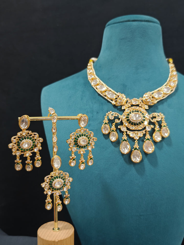 Close-up of an ornate traditional (Bright Gold) Green Collar jewellery set and earrings and maangtikka with Green Colored Stones, Kundan, American Diamond and Pearls. Woman wearing trending artificial Moissanite jewelry for wedding season in India. Bride wearing a high-quality artificial Moissanite jewelry set for wedding rituals.