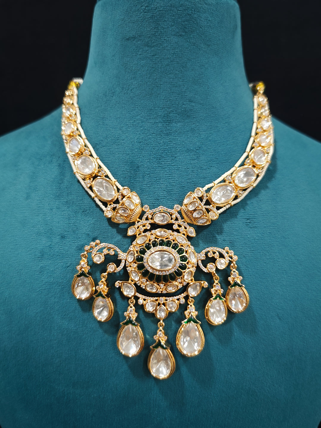 Close-up of an ornate traditional (Bright Gold) Green Collar jewellery set and earrings and maangtikka with Green Colored Stones, Kundan, American Diamond and Pearls. Woman wearing trending artificial Moissanite jewelry for wedding season in India. Bride wearing a high-quality artificial Moissanite jewelry set for wedding rituals.