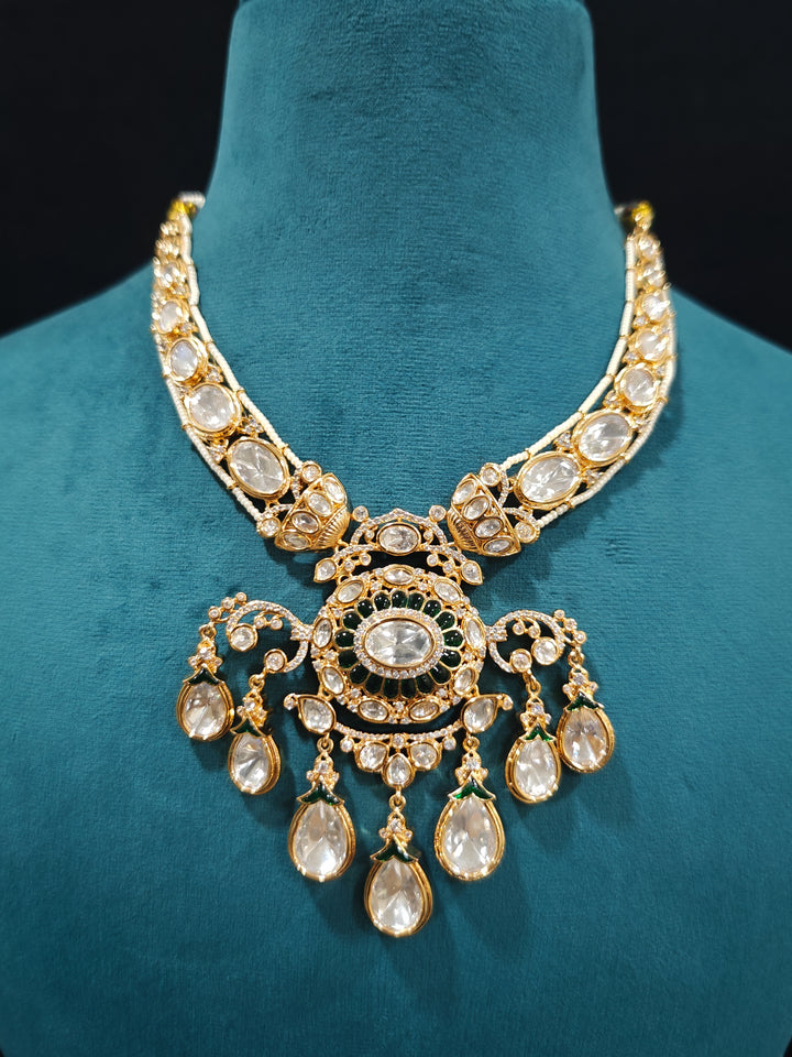 Close-up of an ornate traditional (Bright Gold) Green Collar jewellery set and earrings and maangtikka with Green Colored Stones, Kundan, American Diamond and Pearls. Woman wearing trending artificial Moissanite jewelry for wedding season in India. Bride wearing a high-quality artificial Moissanite jewelry set for wedding rituals.