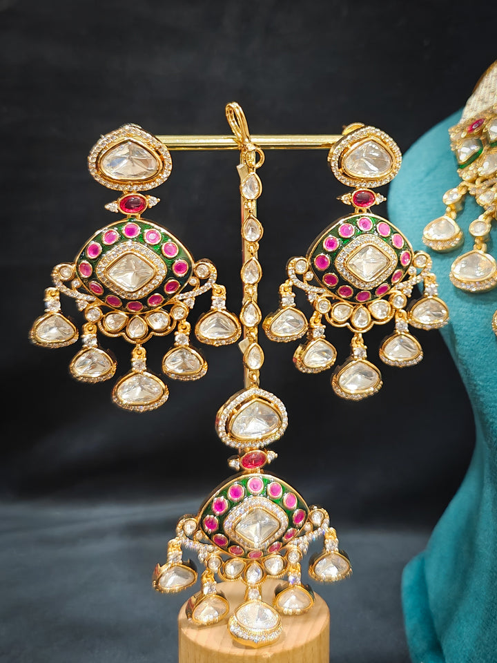 Close-up of an ornate traditional Meenakari Green and Pink Collar jewellery set and earrings and maangtikka with Pink Colored Stones, Uncut Kundan, American Diamond and Meenakari. Close-up of intricate Meenakari detailing in imitation bridal jewelry. Royal Indian bridal styling featuring a handcrafted Meenakari set.