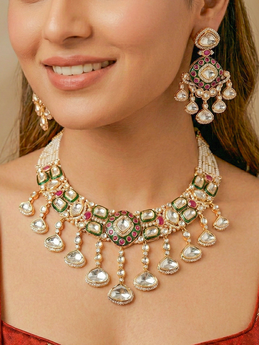 Close-up of a woman wearing an ornate traditional Meenakari Green and Pink Collar jewellery set and earrings and maangtikka with Pink Colored Stones, Uncut Kundan, American Diamond and Meenakari. Bride wearing a colorful Meenakari artificial necklace set for her wedding ceremony. Close-up of intricate Meenakari detailing in imitation bridal jewelry.
