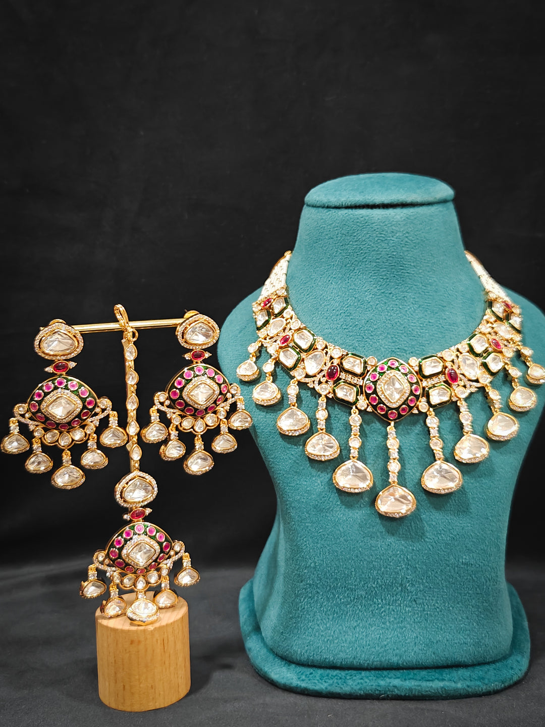 Close-up of an ornate traditional Meenakari Green and Pink Collar jewellery set and earrings and maangtikka with Pink Colored Stones, Uncut Kundan, American Diamond and Meenakari. Close-up of intricate Meenakari detailing in imitation bridal jewelry. Royal Indian bridal styling featuring a handcrafted Meenakari set.