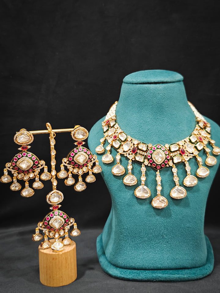 Close-up of an ornate traditional Meenakari Green and Pink Collar jewellery set and earrings and maangtikka with Pink Colored Stones, Uncut Kundan, American Diamond and Meenakari. Close-up of intricate Meenakari detailing in imitation bridal jewelry. Royal Indian bridal styling featuring a handcrafted Meenakari set.
