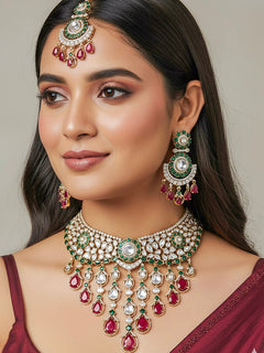 Close-up of a woman wearing an ornate traditional (Bright Gold) Ruby Red and Green Collar jewellery set and earrings and maangtikka with Ruby Red & Green Colored Stones, Kundan, Moissanite and American Diamond. Close-up of intricate detailing in high-quality artificial wedding Moissanite jewelry. Woman wearing a luxury artificial Moissanite jewelry set styled for an Indian wedding celebration.