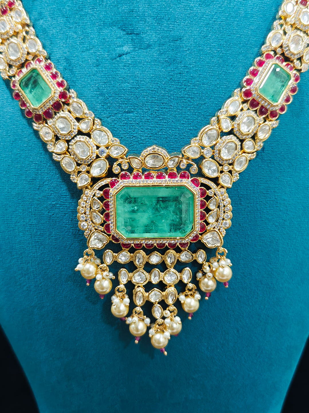 Close-up of an ornate traditional (Bright Gold) Mint Green and Ruby Pink jewellery set and earrings and maangtikka with American Diamond, Pink Colored Stones, Uncut Kundan, Pearls and Doublet Stone. Bride showcasing a premium imitation Moissanite  jewelry set for her reception look. Elegant Indian wedding look completed with luxury artificial  moissanite jewelry set. 