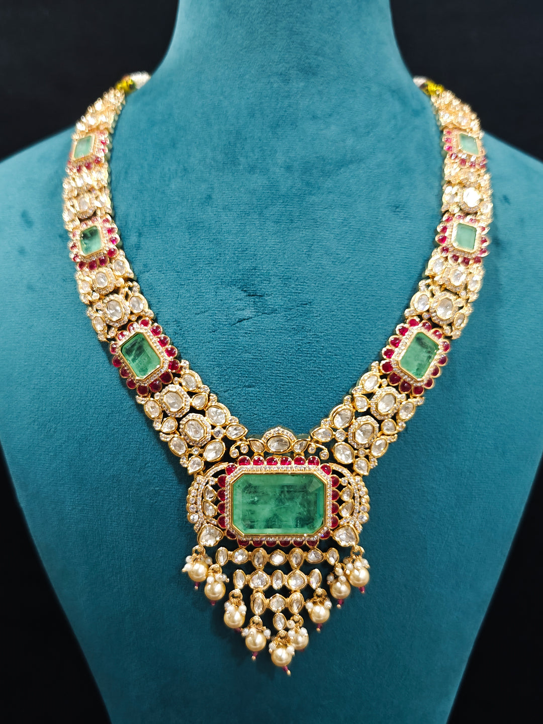 Close-up of an ornate traditional (Bright Gold) Mint Green and Ruby Pink jewellery set and earrings and maangtikka with American Diamond, Pink Colored Stones, Uncut Kundan, Pearls and Doublet Stone. Bride showcasing a premium imitation Moissanite  jewelry set for her reception look. Elegant Indian wedding look completed with luxury artificial  moissanite jewelry set. 