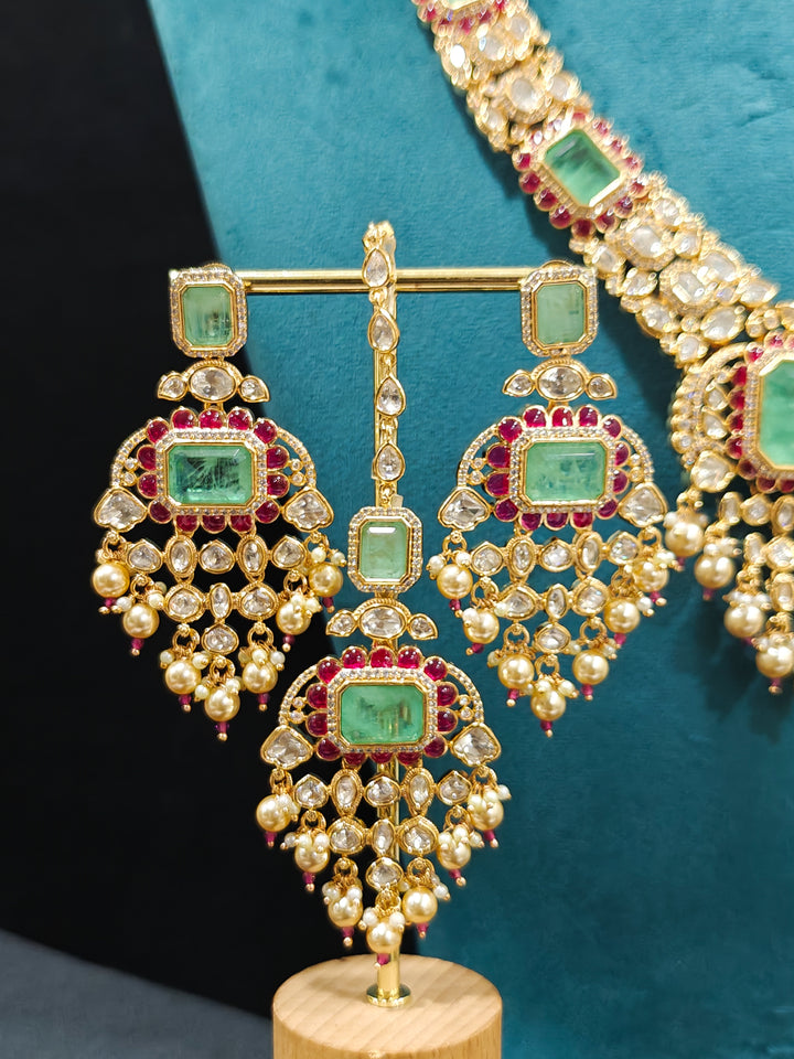 Close-up of an ornate traditional (Bright Gold) Mint Green and Ruby Pink jewellery set and earrings and maangtikka with American Diamond, Pink Colored Stones, Uncut Kundan, Pearls and Doublet Stone. Bride showcasing a premium imitation Moissanite  jewelry set for her reception look. Elegant Indian wedding look completed with luxury artificial  moissanite jewelry set. 