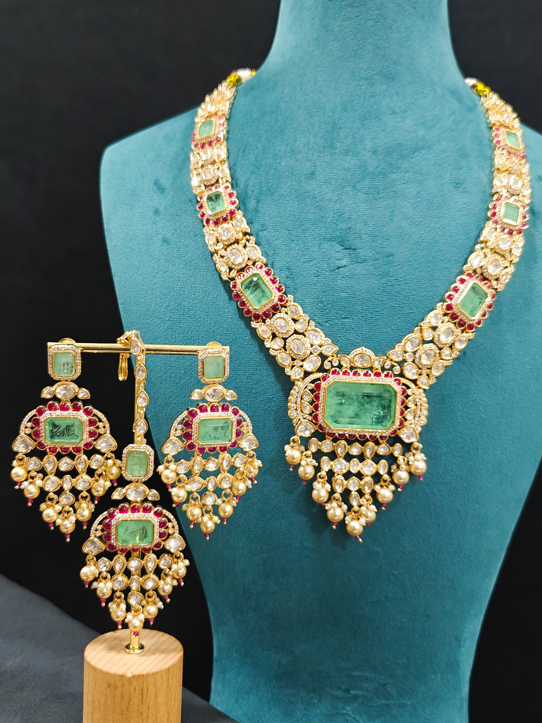 Close-up of an ornate traditional (Bright Gold) Mint Green and Ruby Pink jewellery set and earrings and maangtikka with American Diamond, Pink Colored Stones, Uncut Kundan, Pearls and Doublet Stone. Bride showcasing a premium imitation Moissanite  jewelry set for her reception look. Elegant Indian wedding look completed with luxury artificial  moissanite jewelry set. 