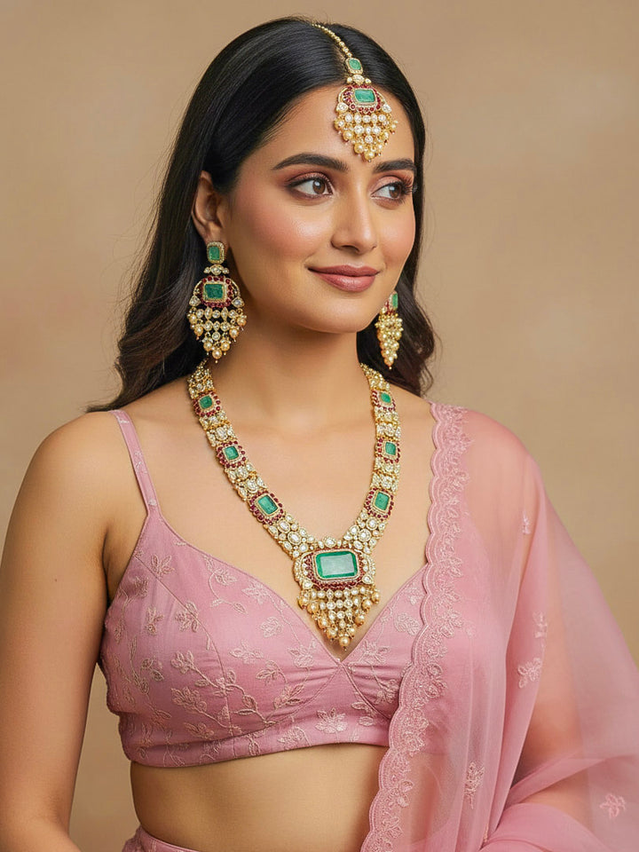 Close-up of a woman wearing an ornate traditional (Bright Gold) Mint Green and Ruby Pink jewellery set and earrings and maangtikka with American Diamond, Pink Colored Stones, Uncut Kundan, Pearls and Doublet Stone. Bride showcasing a premium imitation Moissanite  jewelry set for her reception look. Elegant Indian wedding look completed with luxury artificial  moissanite jewelry set. 
