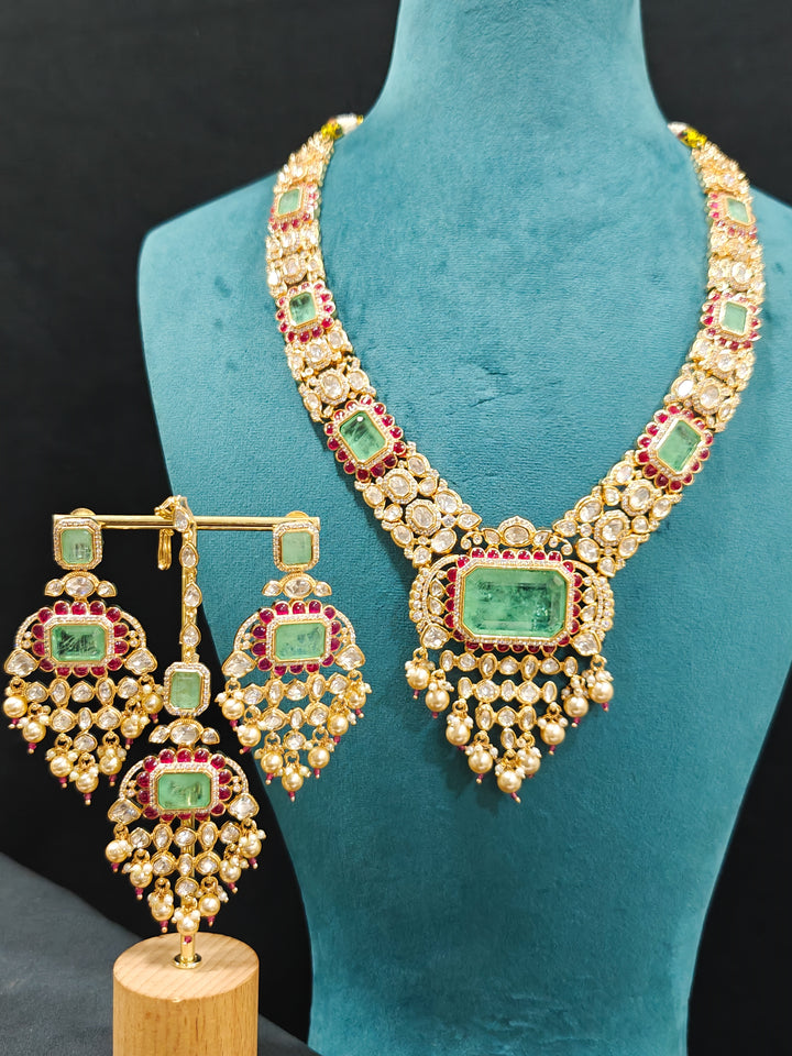 Close-up of an ornate traditional (Bright Gold) Mint Green and Ruby Pink jewellery set and earrings and maangtikka with American Diamond, Pink Colored Stones, Uncut Kundan, Pearls and Doublet Stone. Bride showcasing a premium imitation Moissanite  jewelry set for her reception look. Elegant Indian wedding look completed with luxury artificial  moissanite jewelry set. 